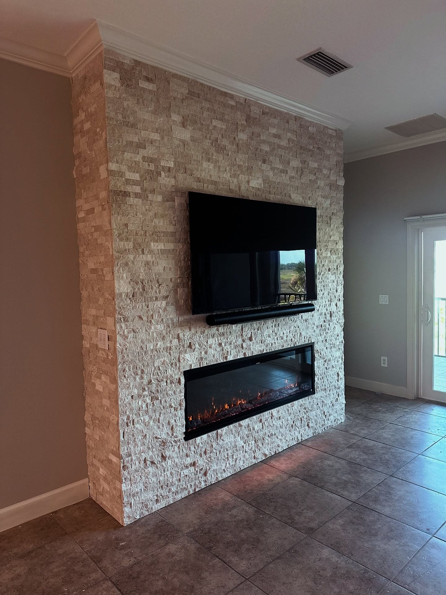 Recessed linear electric fireplace installed flush in a stacked-stone accent wall by AVP Construction JAX
